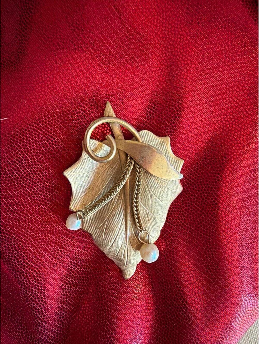 vintage-style brooch features a gold-tone textured leaf design accented with two